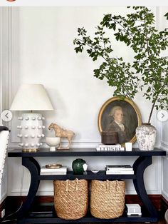 a black table with two baskets and a potted plant on it in front of a white wall