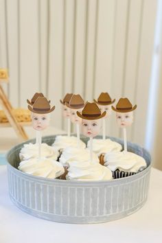 there are cupcakes with hats on top of them in a tin pan and some sticks sticking out of the cake