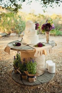 a wedding cake sitting on top of a wooden table covered in flowers and greenery