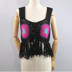 a white mannequin wearing a black top with pink and blue crochet