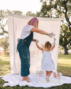 a mother and daughter painting on a white sheet