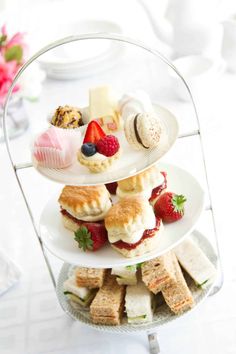 three tiered trays with sandwiches and pastries on them sitting on a table