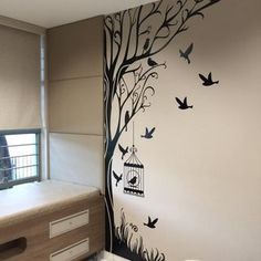 a bedroom with a tree painted on the wall and birds flying around in the air