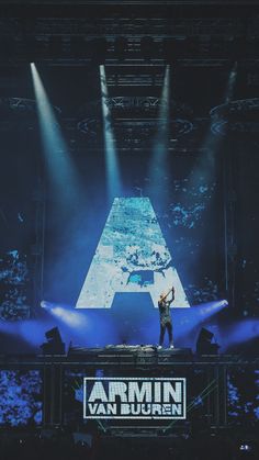 a man standing on top of a stage with his arms in the air