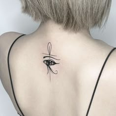 the back of a woman's neck with an eye tattoo