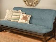 a blue couch with pillows and a clock on the wall