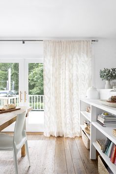 a dining room table with chairs and bookshelves in front of a sliding glass door