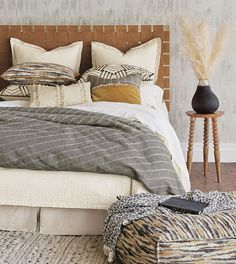 a bed with pillows and blankets on top of it next to a wooden headboard