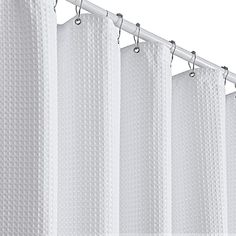 a white shower curtain hanging from a metal rod