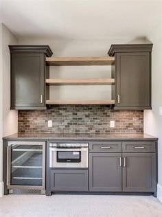 an empty kitchen with gray cabinets and stainless steel appliances