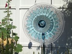 a glass plate sitting on top of a metal pole next to some flowers and plants