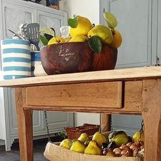 a wooden table topped with a basket filled with lemons and pears on top of it