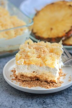 a piece of pineapple delight dessert on a white plate with a fork and pie in the background