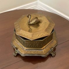 an ornate brass box with a swan on top