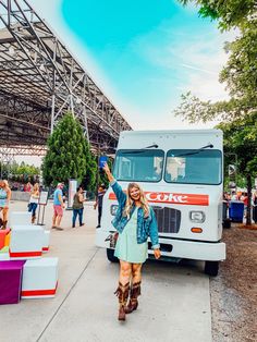 a woman is standing in front of a truck with her hand up to the sky