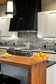 a modern kitchen with stainless steel appliances and wood counter tops, along with white cabinets