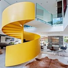 a yellow spiral staircase in the middle of a living room with glass balconies