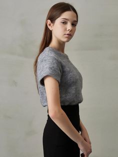 a woman in a gray top and black skirt