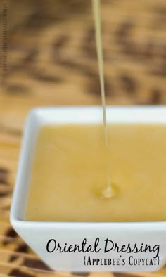 a small white bowl filled with liquid on top of a wooden table