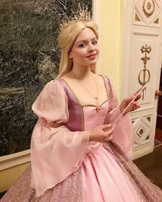 a woman in a pink dress is holding an umbrella and posing for the camera while wearing a tiara