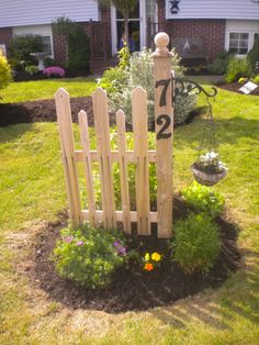 a wooden fence with numbers on it in front of a flower bed and garden area