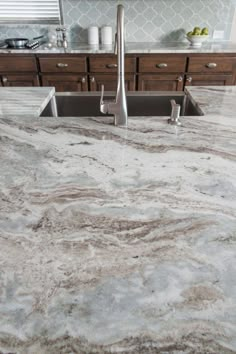 a kitchen with marble counter tops and stainless steel sink faucet in the middle