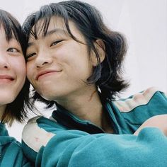 two young people are posing for a photo with their arms around each other's shoulders