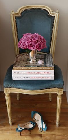 a pair of blue shoes sitting on top of a wooden floor next to a stack of books