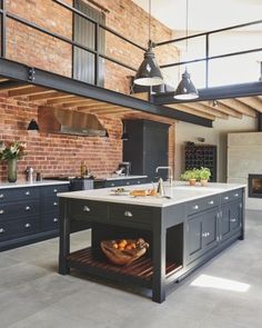 a large kitchen with an island in the center and brick walls on both sides, surrounded by black cabinets