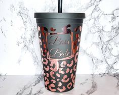 a black and pink cup with a straw in it on a marble countertop next to a marble wall