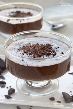 two glasses filled with chocolate pudding on top of a table