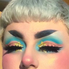 a woman with blue and gold makeup looks at the camera