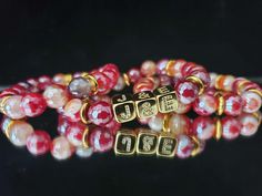 "PLEASE LIST REQUESTED INITIALS AS A NOTE TO SELLER ONLY 2 INITIALS PER BRACELET Handmade, this simple Red and Gold Initial Bracelet Stack is made with Mystic Plated Faceted Red Banded Agate (10mm) Beads, and Gold Hematite Spacer Beads, Featuring Gold 18KT Bling Initial Block Letters ( _&_) . This bracelet is made with Elastic (Stretchy) Band made to fit MOST wrist. Bright Vibrant semi-precious statement designer gemstone bracelet. Handmade with Love, Beautiful Gift packed. Let this Classy and V Adjustable Stackable Red Beaded Bracelets, Adjustable Red Stacked Beaded Bracelets, Adjustable Red Stackable Stretch Bracelet, Red Adjustable Stacked Bracelets, Personalized Red Stretch Bracelet, Casual Style, Initial Bracelet Gold, Handmade Beaded Necklaces, Gold Bead Bracelets, Gold Initial