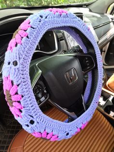 the steering wheel cover is crocheted with pink and purple yarn