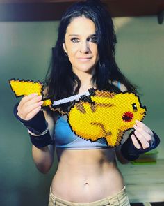 a woman holding up a piece of art made to look like pikachu