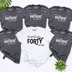 six birthday shirts with the words hello forty printed on them, sitting next to a plant