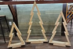 three wooden christmas trees sitting next to each other on top of a hard wood floor