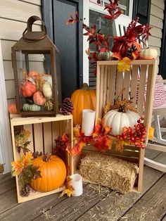 three wooden crates filled with pumpkins, hay and other autumn decorations on a porch