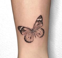 a small butterfly tattoo on the ankle, with black and white butterflies flying around it