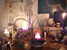 a table with candles, figurines and pictures on it