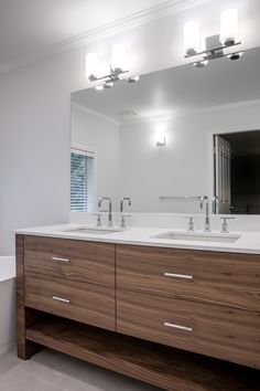 a bathroom with two sinks and a large mirror above the sink is illuminated by three lights