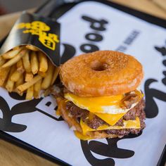 a cheeseburger and fries on a tray with a paper wrapper in the background