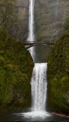 a large waterfall with a bridge over it