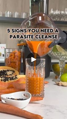 a person pouring orange juice into a glass on top of a counter next to carrots