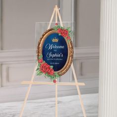 a welcome sign with red flowers on it in front of a white wall and columns