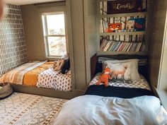 there are two beds in this room with bookshelves on the wall above them