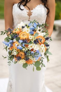 a bride holding a bouquet of orange and blue flowers