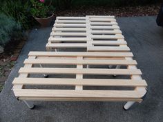 a wooden bed frame sitting on top of a sidewalk