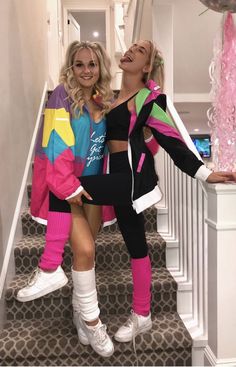 two women in matching outfits standing on the stairs