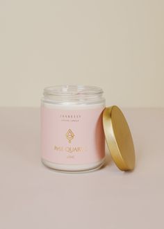 a pink candle with a gold lid next to it